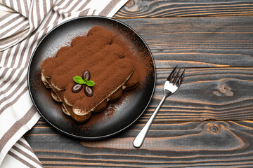 Classic tiramisu dessert on ceramic plate on wooden background