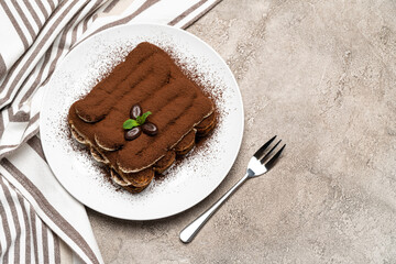 Classic tiramisu dessert on ceramic plate on concrete background