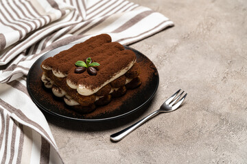 Classic tiramisu dessert on ceramic plate on concrete background