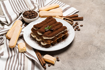 Classic tiramisu dessert and savoiardi cookies on ceramic plate on concrete background