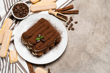 Classic tiramisu dessert and savoiardi cookies on ceramic plate on concrete background