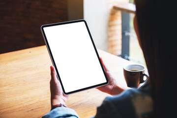 Mockup image of a woman holding digital tablet with blank white desktop screen in cafe