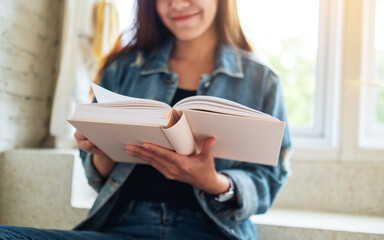 Closeup image of a beautiful asian woman sitting and reading book at home