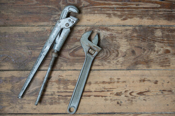 Close-up top view of adjustable wrench and pipe wrenches on a wooden background. Tool for the repair of plumbing pipes and communications. Plumbing tool. Selective focus, shallow depth of field