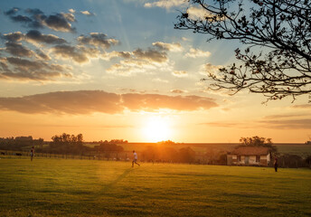 sunset over the field with house in the background