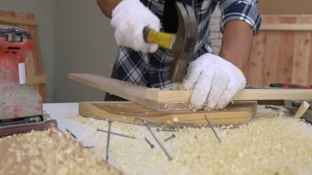 Carpenter working on wood craft at workshop to produce construction material or wooden furniture. The young Asian carpenter use professional tools for crafting. DIY maker and carpentry work concept.