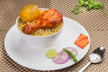 Delicious spicy chicken biryani in white bowl on wooden background, Indian or Pakistani Ramzan food. Beautiful view of traditional spicy Indian food, Iftar meal, Ramadan dinner.