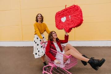 Pretty girls posing with social network icon. Outdoor shot of two female friends.