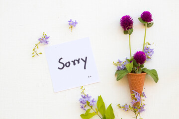sorry message card handwriting with purple flower amaranth in cone arrangement flat lay postcard...