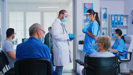Medical team with face mask against coronavirus discussing in hospital waiting room about patient...
