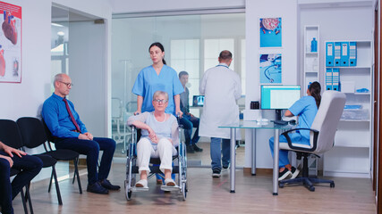Doctor giving nurse radiography of sick patient. Medical assistant and invalid senior woman in...