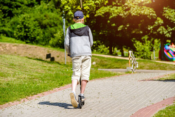 Fototapeta premium A boy rides a scooter in a city Park 