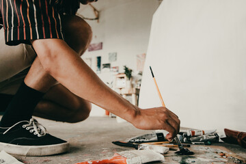 Fototapeta premium unrecognisable male artist mixing colors on palette in workshop