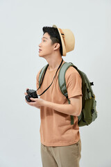 Portrait of cheerful young Asian tourist man holding digital camera and taking photo when standing...