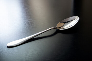 Metal spoon on black wooden table closeup