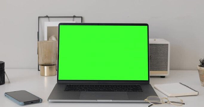 MacBook Pro laptop with mock up chroma key green screen on table of living room, desk set up for work at home - technology concept close up zoom 4k video template