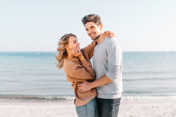 Fototapeta na wymiar Gorgeous girl embracing boyfriend on nature background. Confident brunette man dancing with wife at sea coast.