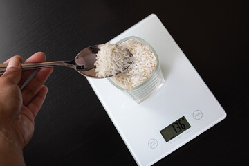 Glass with rice on electronic scales and spoon