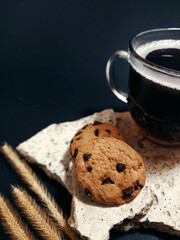 Cookies and hot Americano coffee in a transparent cup, black background.
