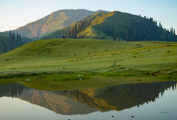 Fototapeta premium lush green landscape with small lake and mountains - mountain reflection on the water - siri paye Medows clear sky