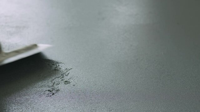Slow motion closeup male worker applying micro concrete plaster coating on the floor with a trowel