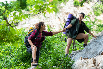Group Hiker woman helping her friend climb up the last section of sunset in mountains. Traveler...