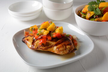 Grilled chicken breast with spicy salsa salad, mango, herbs, onions and peppers, corn chips. Mexican Food.