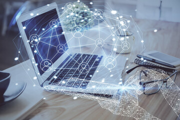 Computer on desktop with social network hologram. Double exposure. Concept of international people connections.
