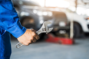 Mechanic close up fixing repairing car engine automobile vehicle parts examining screwing using tools wrench equipment working hard in workshop garage support and service in overall work uniform