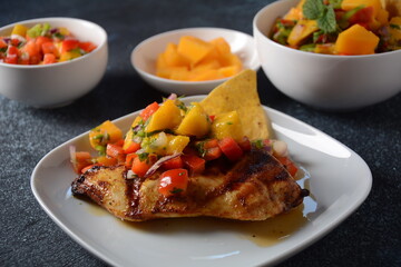 Grilled chicken breast with spicy salsa salad, mango, herbs, onions and peppers, corn chips. Mexican Food.