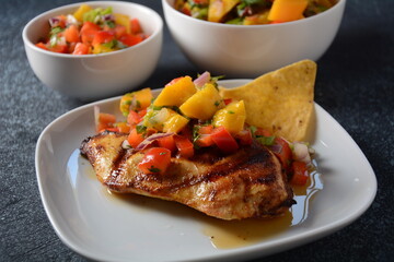 Grilled chicken breast with spicy salsa salad, mango, herbs, onions and peppers, corn chips. Mexican Food.