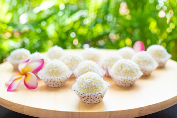 sweet milk balls with coconut flakes on a wooden table on a green background decorated with...