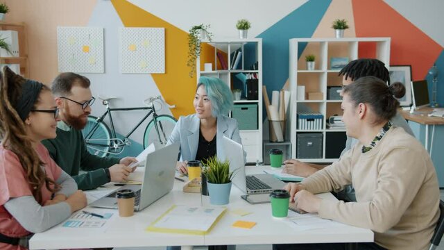 Colleagues multi-ethnic team of creative designers are talking then doing high-five during business meeting in modern office. Success and work concept.