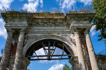 Obraz premium ruins of an old manor house among green trees against a blue sky