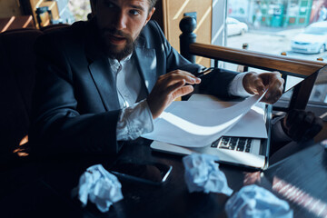 Business man in a cafe sitting at the table documents laptop crumpled paper executive lifestyle emotions