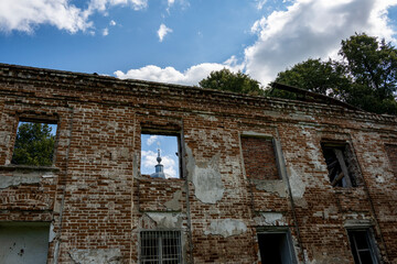 ruins of an old manor house among green trees against a blue sky