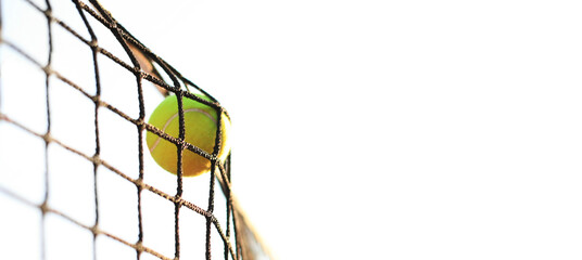 Bright greenish yellow tennis ball hitting the net.