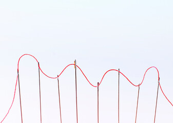 the red thread runs through several needles. business concept