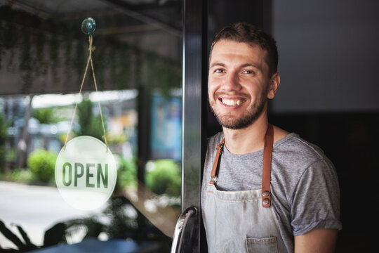 Young Chef owner of sushi restaurant smiling while turning the sign for the reopening of his place after the quarantine due to covid-19. .Small  business open, Thailand, Koh Phangan