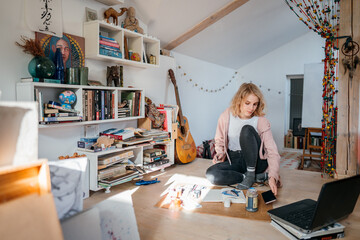 
Blonde student girl draws in her creative
interior room