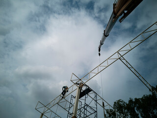 installed steel truss in Cloudy day, Worker is working on main truss, Truck mounted crane at warehouse constructing,