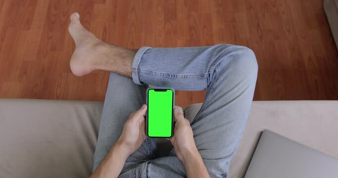 Man Watching Display Mobile iPhone 11. Smartphone Device with Green Screen in Vertical Mode. Hipster Using Smartphone, Browsing Internet, Watching Video Content, Blogs. POV