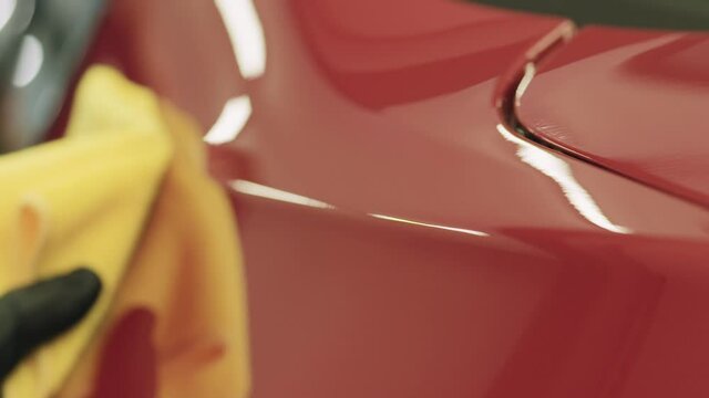 Slow motion closeup of wiping red car with microfiber cloth