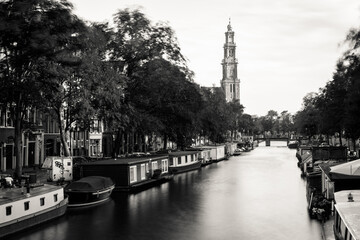 Amsterdam, Holland, the Netherlands - July 6 2020: capture of the typical Amsterdam scenery in black and white with canal, canalo house, clouds and the iconic buildings of the city