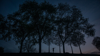 Silueta de una chica entre dos arboles en contraluz