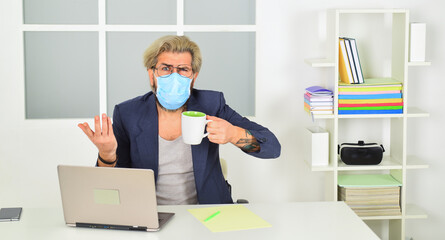Fototapeta na wymiar early morning. work on a remote site. distance learning. infection control and prevention measures. keep your distance. remote-based job. online shopping. man in respirator protective mask in office