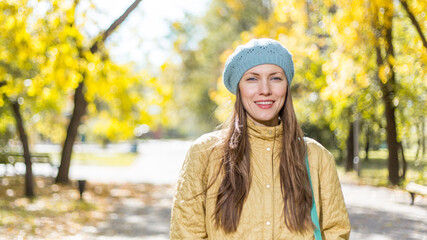 young woman in autumn park wearing warm clothes over golden autumn background