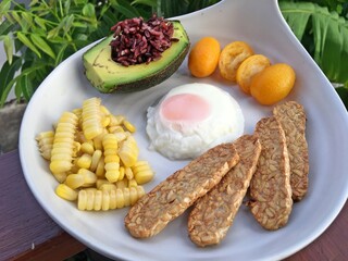 Breakfast set include Berry rice avocado, fried egg, soy tempeh and tiny orange