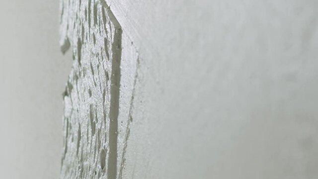 Slow motion closeup worker applying decorative concrete plaster on the wall