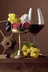 Obraz premium Glass of wine with snacks on a brown background.